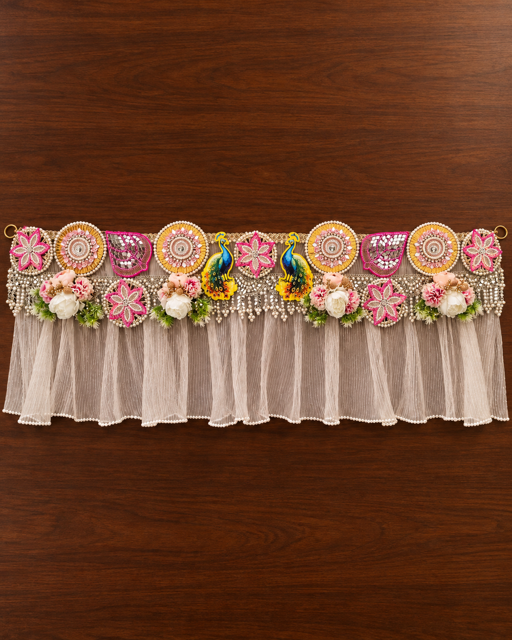 Full length of the 40 inch handmade peacock toran laid flat, with pearl-edged pleated frill and hanging rings at both ends