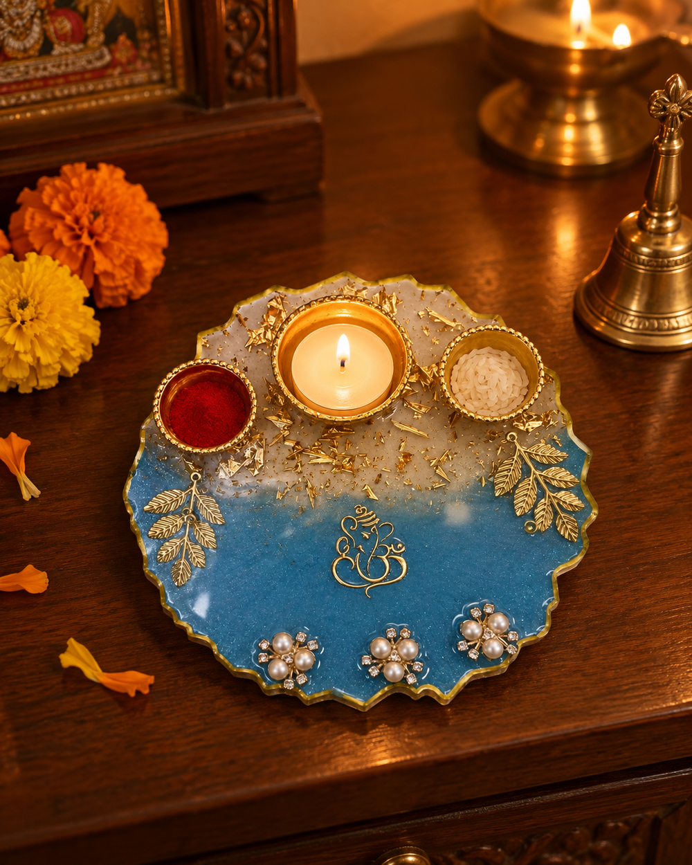 Blue and gold resin pooja thali with a lit tealight on a home mandir shelf