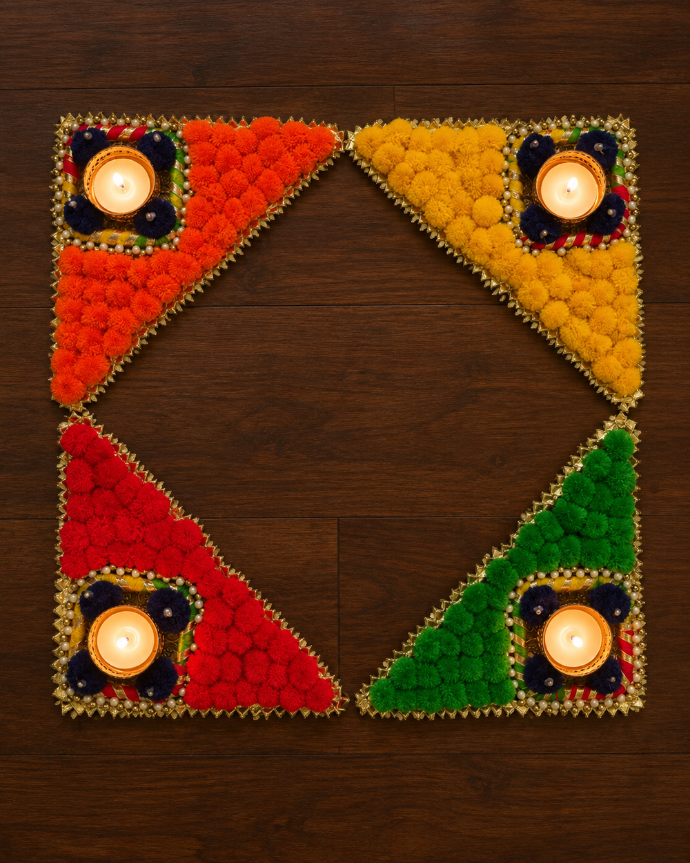 Four triangle rangoli pieces joined as a square frame with four lit tealights