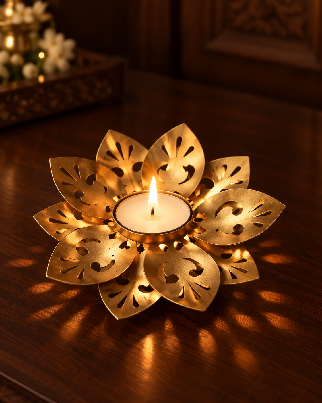 Gold Lotus Tealight Diya lit on a dark wooden table, light falling through its cut-work petals