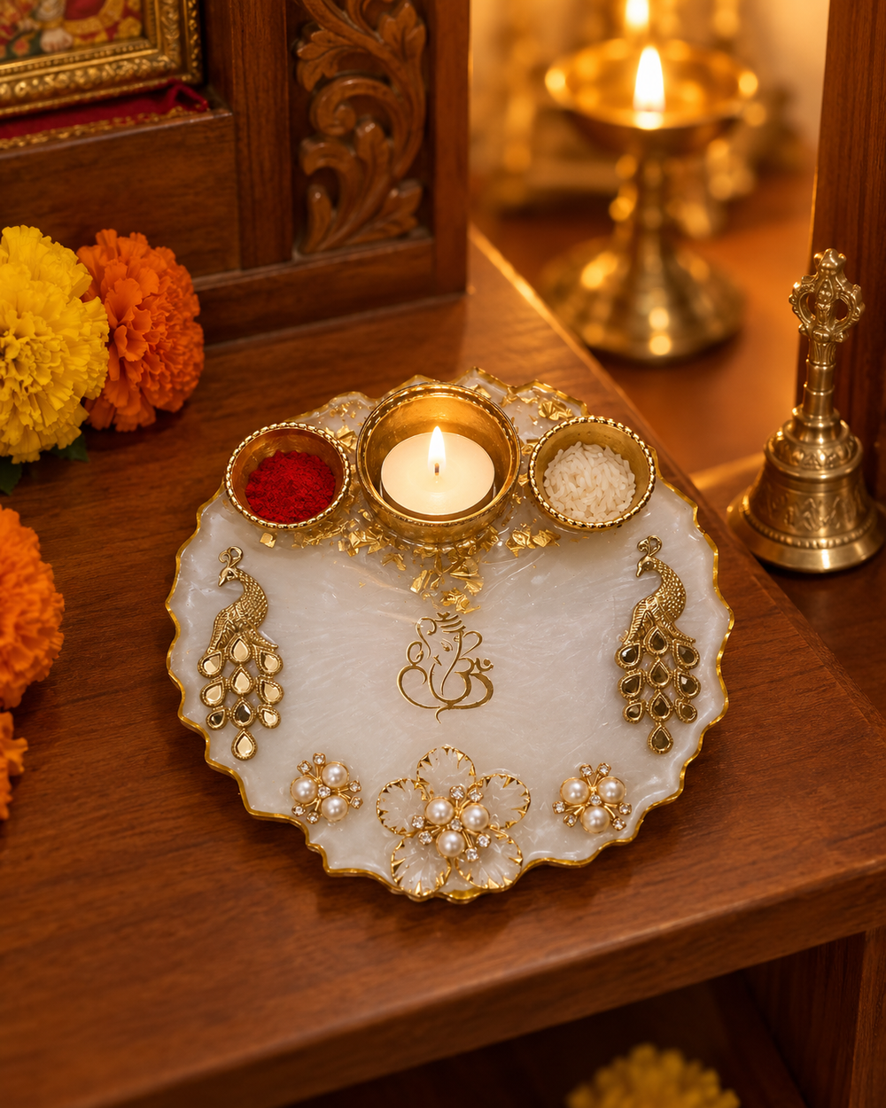 White and gold peacock resin pooja thali with a lit tealight on a home mandir shelf
