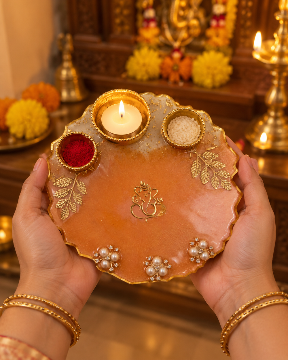 Hands holding the 6-inch peach Ganesha pooja thali during aarti