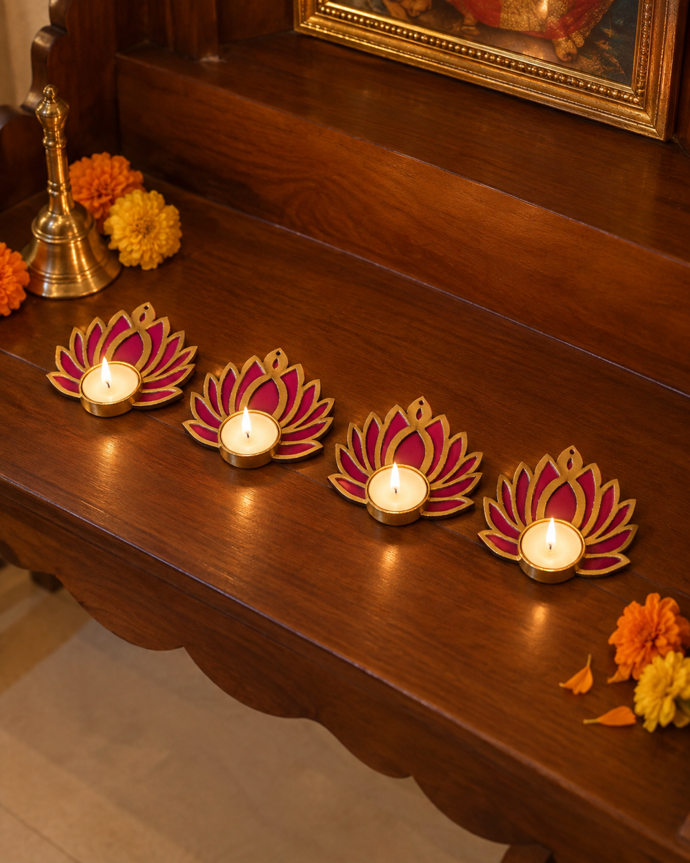 Pack of 4 pink lotus tealight diyas lit in a row on a wooden pooja shelf
