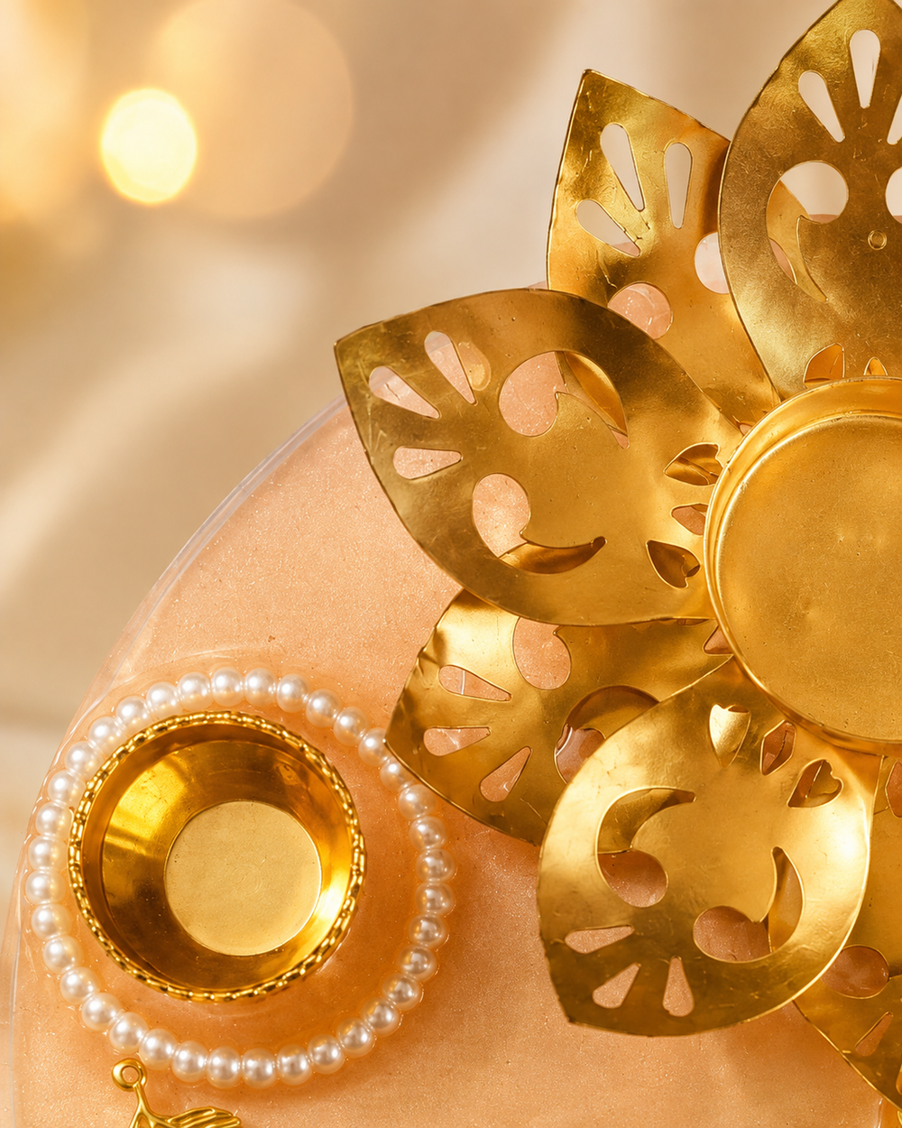 Close-up of the jaali-cut gold lotus diya stand and enamel Ganesha motif on the Giftra resin pooja thali