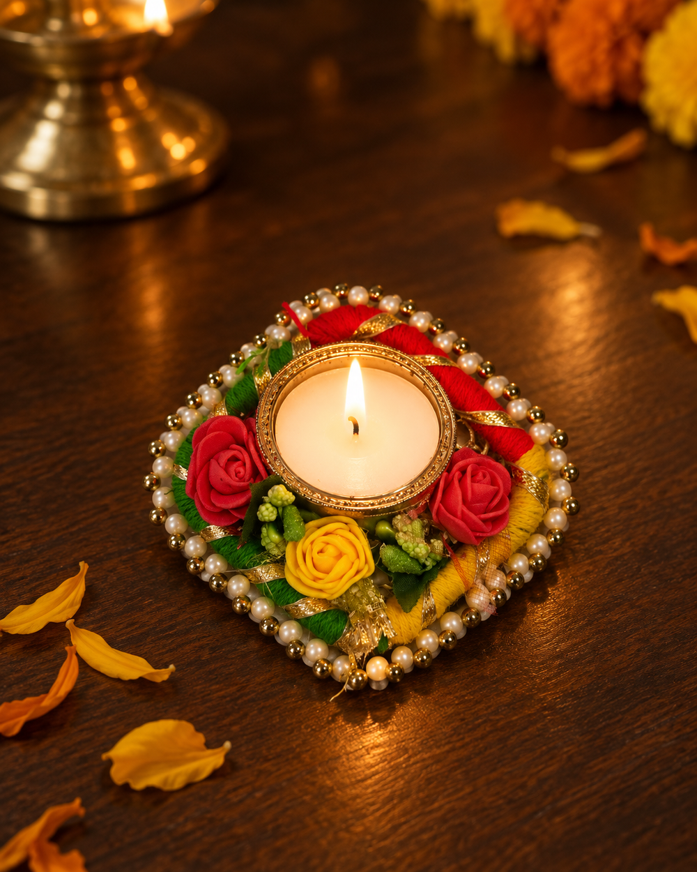 Lit rose garland tealight diya on a wooden table with marigold petals