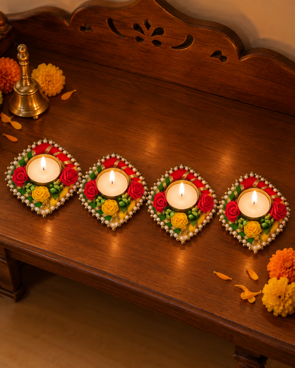 Pack of 4 rose garland tealight diyas lit in a row on a wooden pooja shelf